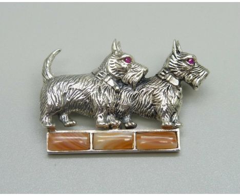 A silver dog brooch with ruby eyes and set with agate, one agate loose 