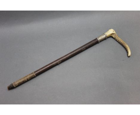 A riding crop with antler handle and inset markers button (illegible), with silver collar, hallmarks rubbed, makers mark poss