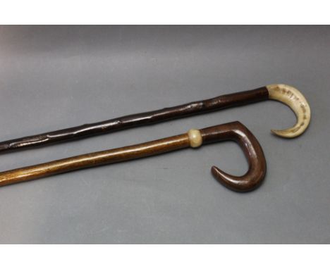 Two walking sticks, the first with wooden handle and horn collar, length 114 cm, the second with horn handle, length 23 cm.