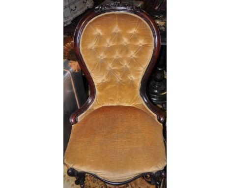 A Victorian mahogany spoonback nursing chair upholstered in button gold draylon on cabriole legs