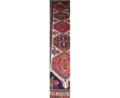 A Persian Kazak style ivory ground runner woven central hexagonal medallions within a triple floral border, approx 300 x 76cm