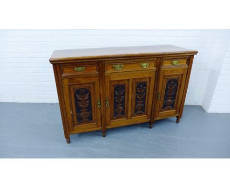 An Arts & Crafts style oak sideboard having a moulded top over three short drawers and three panel doored cabinets raised on 