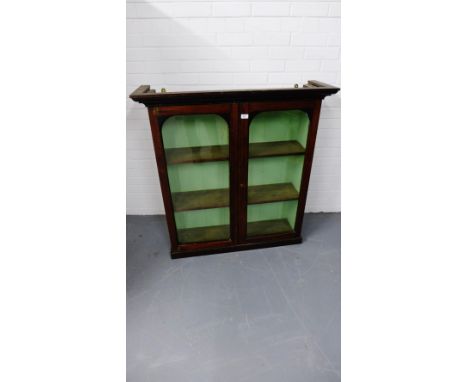 A mahogany bookcase having two glazed panel doors enclosing a shelved interior, 104 x 110 cm