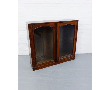 A late 19th century mahogany bookcase having two glazed panel doors enclosing shelved interior raised on a fixed plinth base,