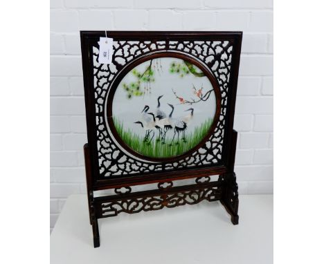 Chinese needlework screen, contained in a circular revolving glazed panel in a stained wood fretwork surround, on shaped side