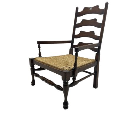 Georgian design oak country low armchair, waived ladder back over rush seat, raised on turned  supports united by stretchers;