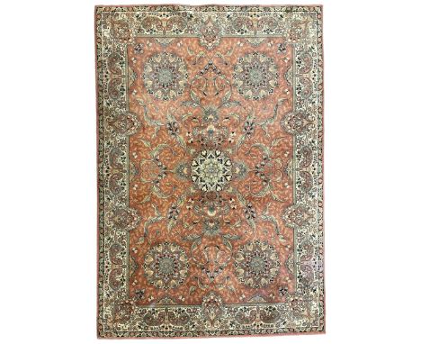 Persian design peach ground carpet, central floral medallion surrounded by scrolling foliage, decorated all over with stylise