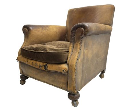 Early 20th century club armchair, upholstered in tan leather with upholstered seat cushion in brown fabric, rolled arms, on t