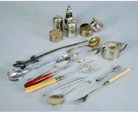 A selection of silver plated items including four condiments, a pair of nut crackers, napkin rings, bread fork, pickle forks,