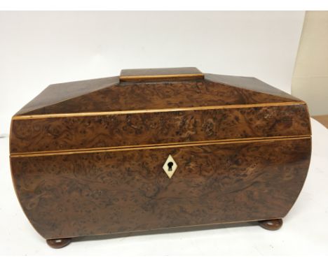 A burr walnut tea caddy with a shaped top and inverted sides with a well fitted interior with mixing bowl the sides with wood