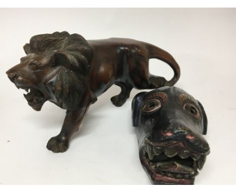 A carved hardwood sculpture of a lion length 40cm and a tribal art painted wood dog mask. (2)