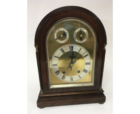 An Edwardian Mahogany mantel or table clock the arch case with pillar ornamentation with a brass dial and two subsidiary silv