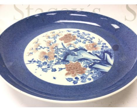 A Chinese blue and white and copper red floral porcelain charger, 30cm wide. This lot cannot be posted