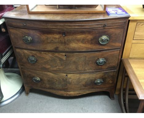 A late George III mahogany bow fronted chest of drawers fitted with a brushing slide above three drawers on swept bracket fee