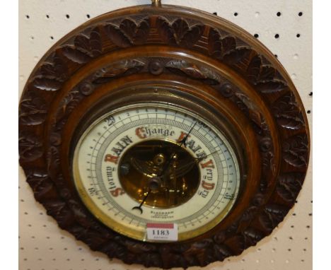 An early 20th century floral relief carved walnut circular aneroid barometer, signed Blackham Optician Leamington, dia.29cm