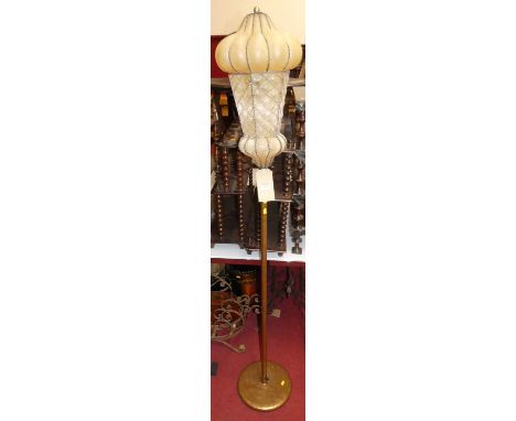 A gilt decorated tubular metal standard lamp, with a blown yellow glass shade within wirework integral frame, height 176cm