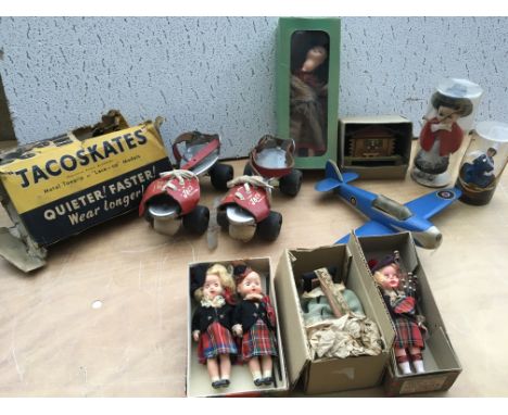 A collection of boxed dolls with a hand made wooden aeroplane and a pair of vintage roller skates