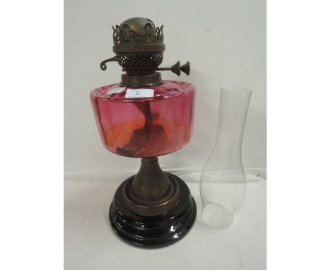 A vintage oil burning lamp made by Veritas lighting co, with cranberry well ceramic base and brass fitments