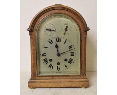 An Edwardian mantel clock, the 15 cm arched silvered dial with Roman numerals and subsidiary Slow/Fast and Chime/Silent dials