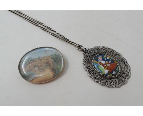 A gold coloured metal mounted oval miniature brooch, decorated a Gothic arch, 4 cm wide and an Eastern enamel silver coloured