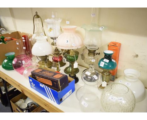 An oil lamp, with cranberry and frosted glass shade, 50 cm high, other oil lamps, shades and accessories (qty) 