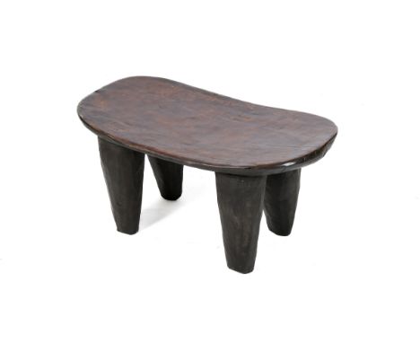 A Baule low wood stool. The slightly dipped seat with rounded corners, raised on tapering supports. H32.5cm x W63cm x D38cm. 