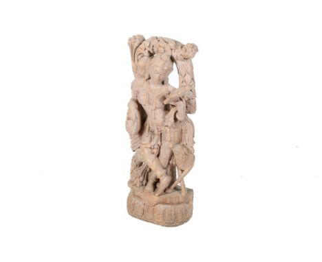 A large red stone carving of an Apsara. Adorned with jewels, standing on a lotus base. H92cm.