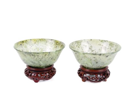 A pair of Chinese jade bowls on stands. Of translucent mottled colour, with outturned lip and raised on a short, straight foo