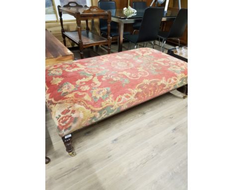 A LARGE POUFFE WITH BRASS CASTERS
