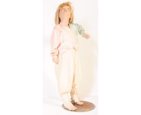 A 20th century vintage children shop display mannequin dressed in a pair of pyjamas and being raised on circular metal base. 