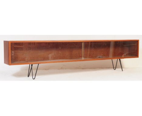A retro vintage mid 20th century teak wood low book case. Of rectangular form with twin sliding glazed doors with interior. A