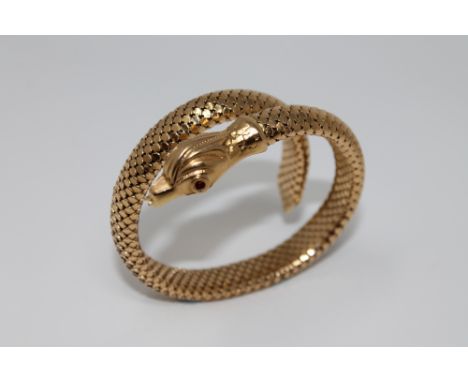 An 18ct gold snake bracelet with ruby eyes, 36.8g gross. CONDITION REPORT: The snakes head is stamped '750' for 18ct gold. Th