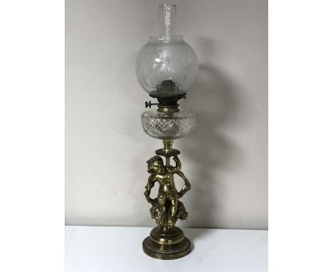 An antique oil lamp with glass chimney and shade on a cherub base CONDITION REPORT: Glass shade with numerous tiny fleabite c