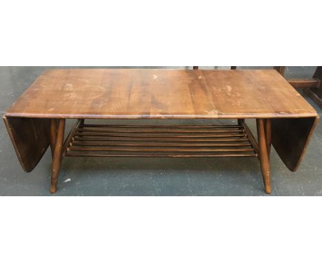 A mid century Ercol oak coffee table with drop ends and magazine shelf 