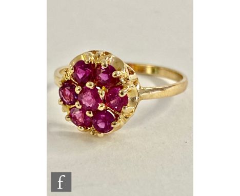 An 14ct ruby daisy cluster ring comprising seven claw set stones to knife edged shoulders, weight 2.2g, ring size N. 