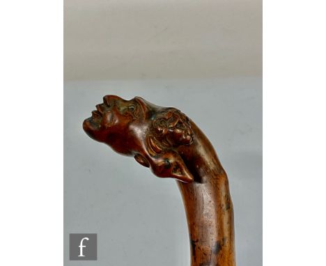 A 19th Century carved fruit wood child's walking stick the grip carved with a lion, dog and two further faces, length 78cm. 