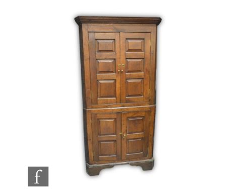 A George III oak floorstanding corner cupboard, enclosed by a double pair of fielded paneled doors below a fluted cornice, sh