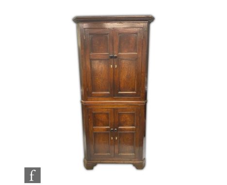 A George III oak floorstanding corner cupboard enclosed by a double pair of panel doors, fixed shelf interior below a fluted 