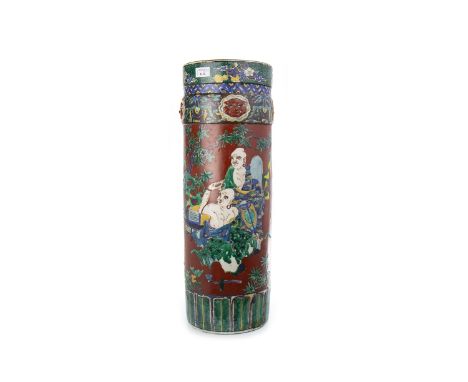 LATE 19TH CENTURY CHINESE CYLINDRICAL STICK STAND, decorated with devil-type masks in relief above painted figures, on a red 