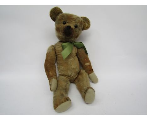 An early 20th Century straw filled jointed bear with black boot button eyes and hump back, pads replaced, 50 cm tall