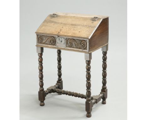 A 17TH CENTURY OAK BIBLE BOX, the slant-front box with scroll-carved front, now raised on a bobbin and reel turned stand. 87c