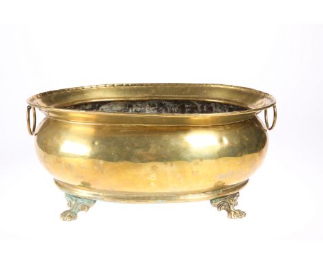 A GEORGIAN STYLE OVAL BRASS WINE COOLER, EARLY 20TH CENTURY, with ring handles and paw feet. 40.5cm wide