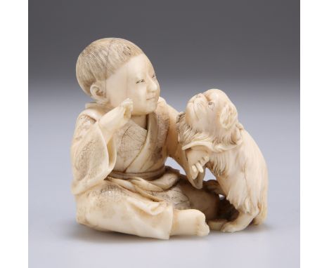 A JAPANESE IVORY NETSUKE, MEIJI PERIOD, carved as a boy playing with a dog. 6cm high