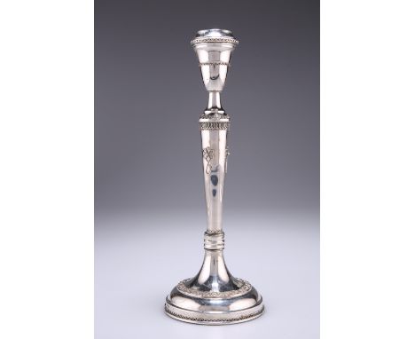 A CONTINENTAL SILVER METAL CANDLESTICK, with tapering stem and urn-shaped sconce above a circular base, decorated with applie
