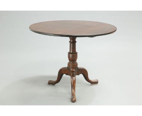 A LARGE GEORGE III OAK TILT-TOP TRIPOD TABLE, the circular top raised on a turned stem continuing to hipped downswept legs te