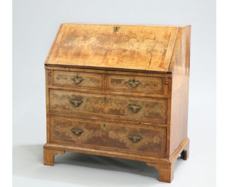 AN EARLY 18TH CENTURY FEATHERBANDED WALNUT SLANT-FRONT BUREAU,&nbsp;with quarter-veneered top and slope, the interior with pi