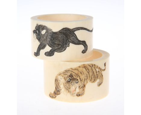 TWO IVORY NAPKIN RINGS, CIRCA 1900, circular, each carved and coloured, the first with two tigers, the second with a lion and