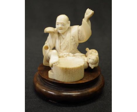 Antique Japanese carved ivory seated gentleman with bird on shoulder and cat to side, on timber stand, C1930's, signed to bas