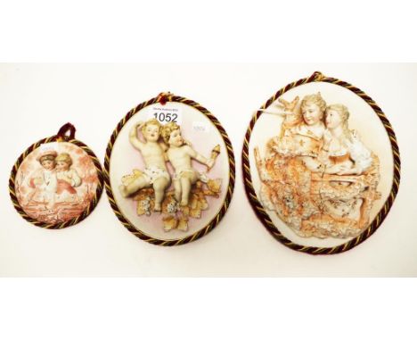Three graduated bisque ceramic plaques each with Figures in relief, (height 20cm approx, largest).