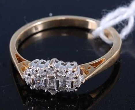 A modern 9ct gold diamond dress ring, arranged as three baguettes within a surround of small brilliants, total diamond weight